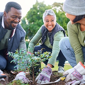 Group of volunteers smiling while planting a tree