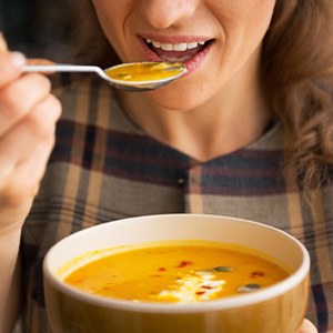 A woman eating from a bowl of soup