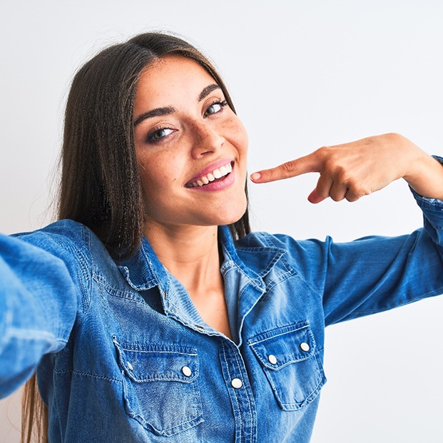 Smiling woman pointing to her white teeth