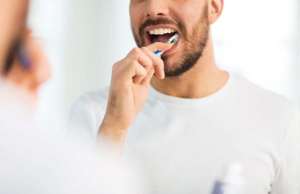 Man in white t-shirt brushing teeth