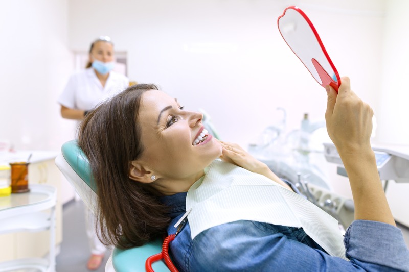 Patient smiling in mirror after cosmetic dentistry