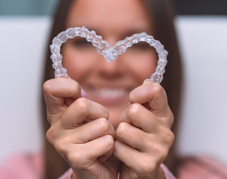 Woman holding clear aligners in heart shape